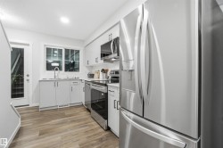 Kitchen featuring appliances with stainless steel finishes, light wood-style floors, and white cabinetry - 