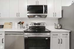 Kitchen with stainless steel appliances, white cabinetry, and tasteful backsplash - 