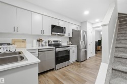 Kitchen featuring appliances with stainless steel finishes, light wood finished floors, white cabinets, recessed lighting, and light stone countertops - 