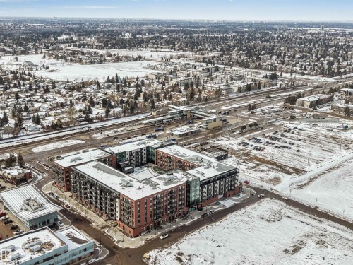 Aerial view of the property and its surrounding area, featuring a multi-story building with balconies, a snow-covered roof, and a visible parking area - 10865 21 Ave, Edmonton, AB - Outdoor With View