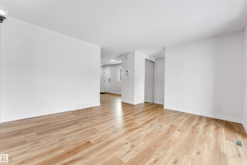 This interior space features light-toned wood flooring and white walls - 10865 21 Ave, Edmonton, AB - Indoor Photo Showing Other Room