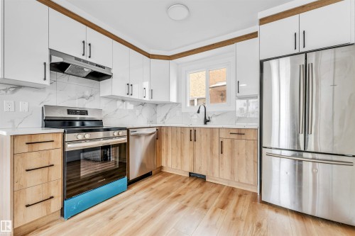 The kitchen features light wood flooring, white upper cabinetry, and light wood lower cabinetry - 10865 21 Ave, Edmonton, AB - Indoor Photo Showing Kitchen With Upgraded Kitchen