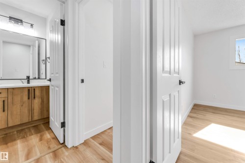 The bathroom features a wooden vanity with a white countertop and a contemporary black faucet - 10865 21 Ave, Edmonton, AB - Indoor Photo Showing Other Room