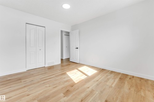 Bright room featuring light wood-style flooring, white walls, and a white bi-fold closet door - 10865 21 Ave, Edmonton, AB - Indoor Photo Showing Other Room