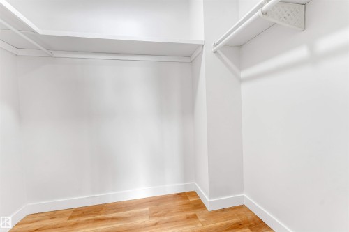 The property features a spacious closet with hardwood floors, white walls, and built-in shelving and hanging rods - 10865 21 Ave, Edmonton, AB - Indoor