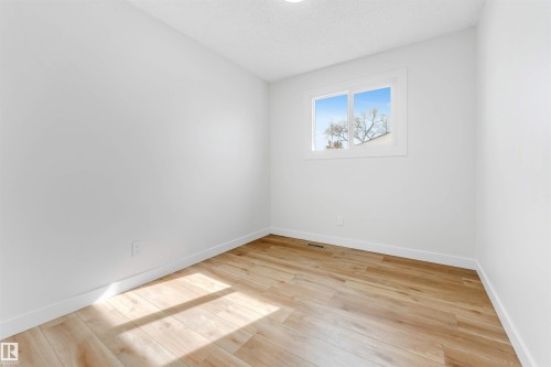 The room features light-toned wood flooring and a window providing natural illumination - 10865 21 Ave, Edmonton, AB - Indoor Photo Showing Other Room