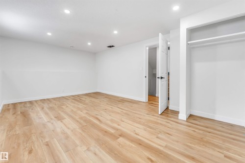 This room features light-toned wood-style flooring, white walls, and recessed lighting - 10865 21 Ave, Edmonton, AB - Indoor Photo Showing Other Room