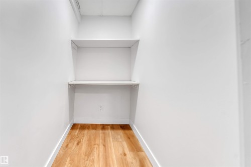 This space features built-in white shelving, light hardwood flooring, and white walls - 10865 21 Ave, Edmonton, AB - Indoor With Storage