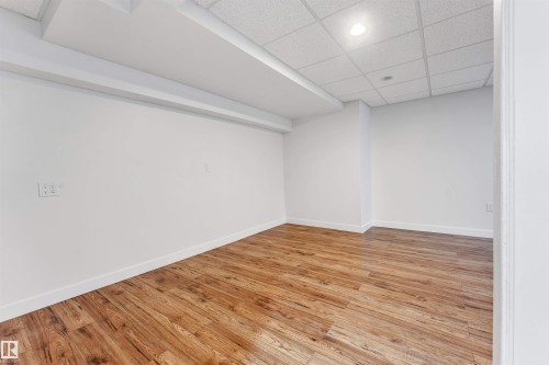 This versatile room features light wood-look flooring, crisp white walls, and a drop ceiling with recessed lighting - 10865 21 Ave, Edmonton, AB - Indoor Photo Showing Other Room