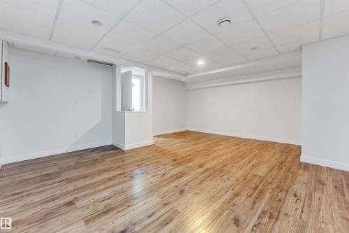 This spacious room features light wood-style flooring and a white drop ceiling with recessed lighting - 10865 21 Ave, Edmonton, AB - Indoor Photo Showing Other Room