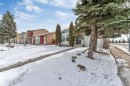 The property features a front yard with a concrete pathway leading to the entrance, mature evergreen trees, and a wooden fence - 10865 21 Ave, Edmonton, AB  - Outdoor 