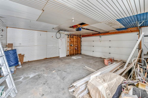 The property features a spacious garage with a white sectional door, a concrete floor, and slat wall panels - 10865 21 Ave, Edmonton, AB - Indoor Photo Showing Garage