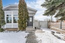 The property features a dark gray front door, a light gray exterior with white trim, and a paved walkway leading to the entrance - 10865 21 Ave, Edmonton, AB  - Outdoor 