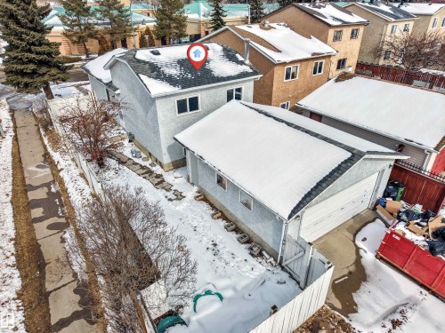 The property includes a detached garage with a white garage door, and a partially fenced yard - 10865 21 Ave, Edmonton, AB - Outdoor