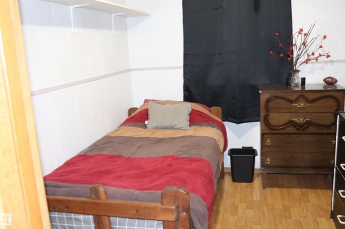 This room features light wood flooring, white walls with an accent trim, and a dark wooden dresser - 5512 50Th Ave, Wetaskiwin, AB - Indoor