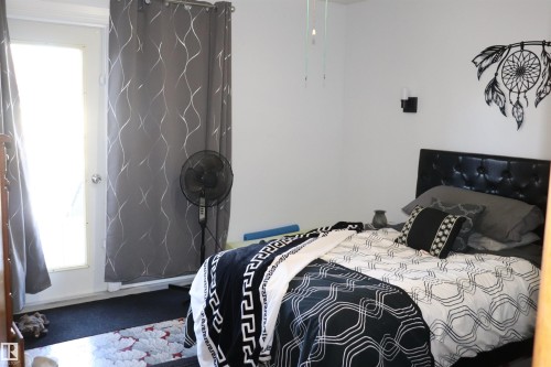 This room features a white door, a dark colored bed frame, and light colored walls - 5512 50Th Ave, Wetaskiwin, AB - Indoor Photo Showing Bedroom