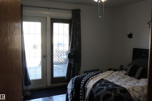 Bedroom featuring a glass-paneled door leading to an outdoor deck, a ceiling fan, and sconce lighting - 5512 50Th Ave, Wetaskiwin, AB - Indoor Photo Showing Bedroom