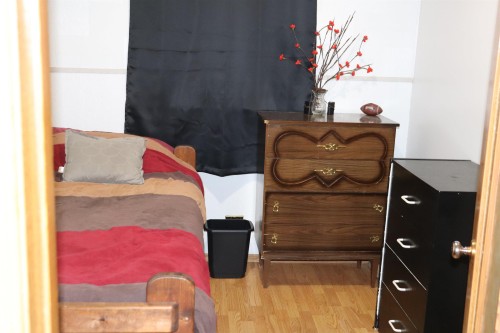 This room features light-toned wood flooring and a classic wooden dresser with decorative hardware - 5512 50Th Ave, Wetaskiwin, AB - Indoor