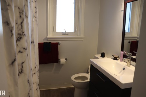 The bathroom features a window, a vanity with a white sink, and a mirrored cabinet - 5512 50Th Ave, Wetaskiwin, AB - Indoor Photo Showing Bathroom