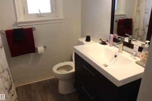 Bathroom with a white vanity sink, dark wood cabinet with drawers, and a wall-mounted mirror - 5512 50Th Ave, Wetaskiwin, AB - Indoor Photo Showing Bathroom