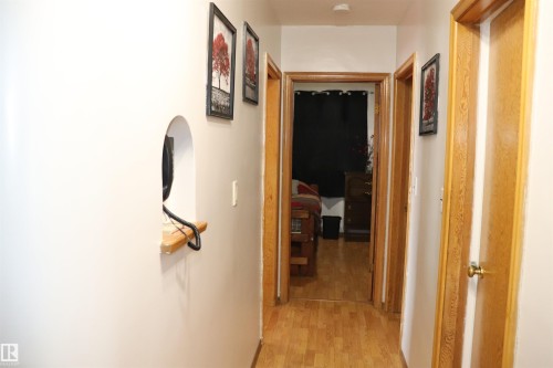 Hallway featuring light wood flooring, several wooden doors, and a wall niche with a wooden shelf - 5512 50Th Ave, Wetaskiwin, AB - Indoor Photo Showing Other Room