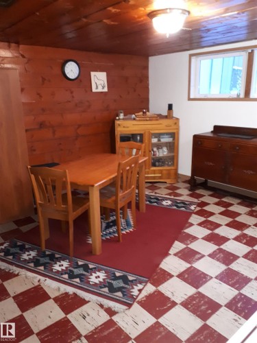 The property features wood paneled walls and ceiling, a checkerboard floor, and a window providing natural light - 5512 50Th Ave, Wetaskiwin, AB - Indoor Photo Showing Other Room