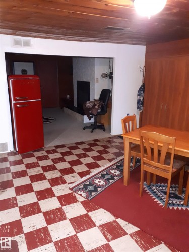 This space features a wooden ceiling, a red and white checkered floor, and a red refrigerator - 5512 50Th Ave, Wetaskiwin, AB - Indoor Photo Showing Other Room