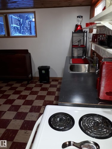 The kitchen features a stainless steel sink, a compact electric range, white walls, and a checkerboard floor - 5512 50Th Ave, Wetaskiwin, AB - Indoor Photo Showing Kitchen
