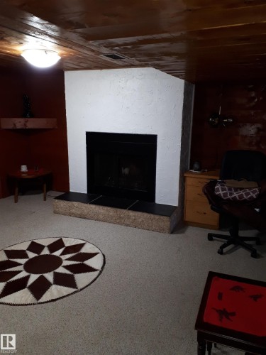 This room features a white fireplace with a black firebox and a tiled hearth - 5512 50Th Ave, Wetaskiwin, AB - Indoor With Fireplace