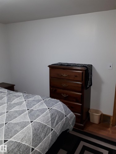 Room featuring white walls and a warm-toned wooden chest of drawers with decorative handles - 5512 50Th Ave, Wetaskiwin, AB - Indoor Photo Showing Bedroom