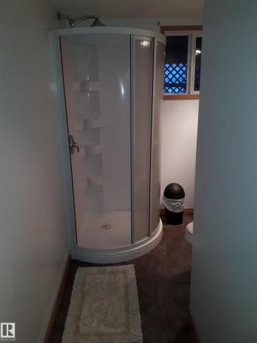 The bathroom features a standalone shower enclosure with a curved glass door and a window - 5512 50Th Ave, Wetaskiwin, AB - Indoor Photo Showing Bathroom