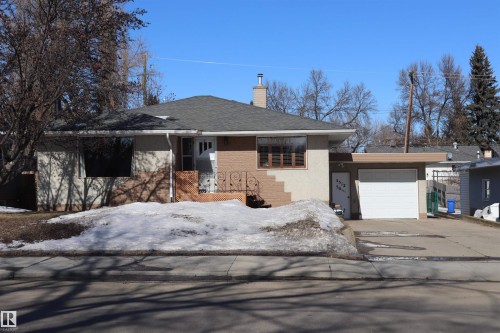 Exterior view of the property featuring a brick and stucco facade, a dark shingled roof, and an attached garage with a white door - 5512 50Th Ave, Wetaskiwin, AB - Outdoor