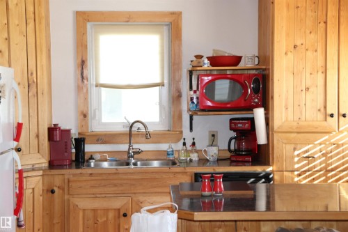 The kitchen features light-toned wooden cabinetry and dark countertops - 5512 50Th Ave, Wetaskiwin, AB - Indoor Photo Showing Kitchen With Double Sink