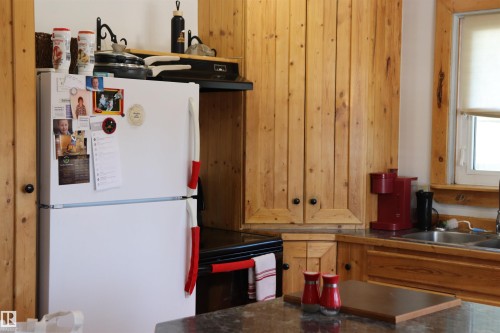 The kitchen features natural wood cabinetry and trim, a stainless steel sink, and ample countertop space - 5512 50Th Ave, Wetaskiwin, AB - Indoor Photo Showing Kitchen With Double Sink