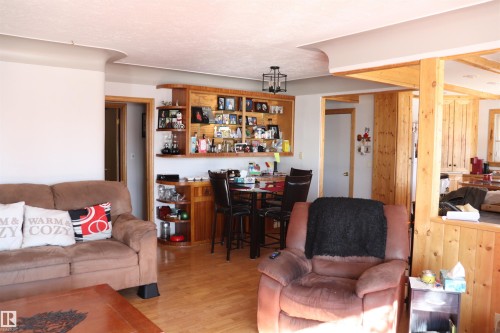 The property features hardwood floors, a built-in bar with shelving, and light wood paneled walls - 5512 50Th Ave, Wetaskiwin, AB - Indoor Photo Showing Living Room
