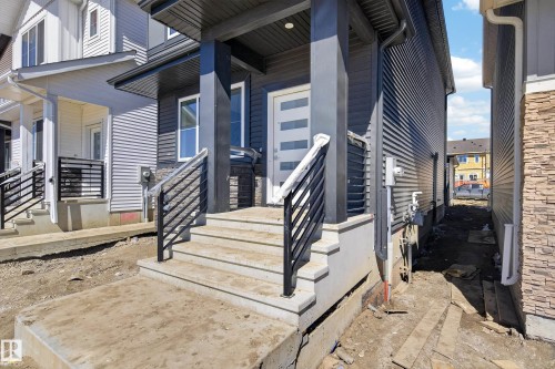 Contemporary dark grey exterior featuring horizontal siding, stone veneer accents, and a covered entryway - 408 Crystal Creek Link, Leduc, AB - Outdoor