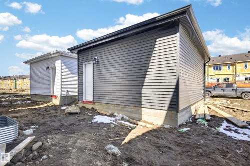 Newly constructed outbuilding featuring dark gray horizontal siding, a white entry door, and a dark gray gutter system - 408 Crystal Creek Link, Leduc, AB - Outdoor