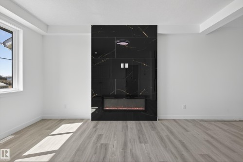 Feature wall with black and gold-veined tile surround and an integrated electric fireplace - 408 Crystal Creek Link, Leduc, AB - Indoor With Fireplace