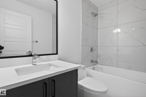 Contemporary bathroom featuring a white vanity countertop, integrated sink, chrome faucet, and dark cabinetry - 408 Crystal Creek Link, Leduc, AB - Indoor Photo Showing Bathroom