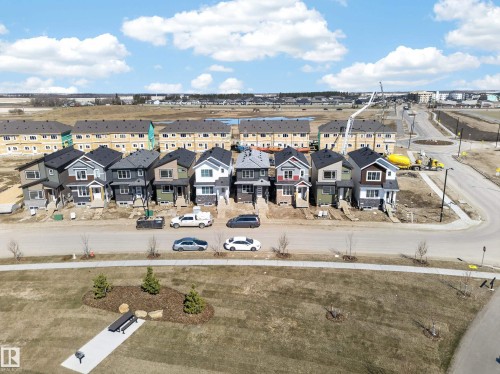 Contemporary residential streetscape featuring a row of detached homes with varied exterior finishes, including siding and stone accents - 408 Crystal Creek Link, Leduc, AB - Outdoor With View