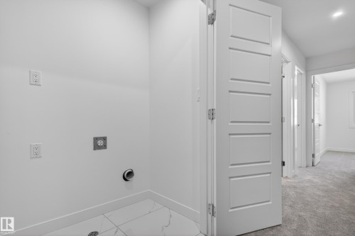 Dedicated laundry area featuring white walls, a white baseboard, and a white tile floor with subtle veining - 408 Crystal Creek Link, Leduc, AB - Indoor Photo Showing Other Room