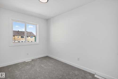 Room featuring a double-pane window with white trim, light grey carpeting, white baseboards, and a flush-mount ceiling light fixture - 408 Crystal Creek Link, Leduc, AB - Indoor Photo Showing Other Room
