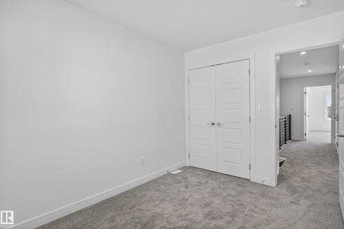 Plush gray carpeting extends throughout, complemented by crisp white baseboards and walls - 408 Crystal Creek Link, Leduc, AB - Indoor Photo Showing Other Room