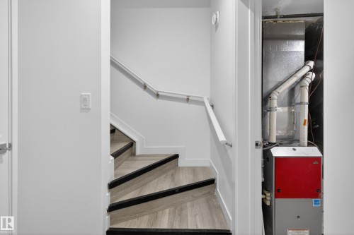 Light wood-finish staircase with black tread accents and a white handrail - 408 Crystal Creek Link, Leduc, AB - Indoor