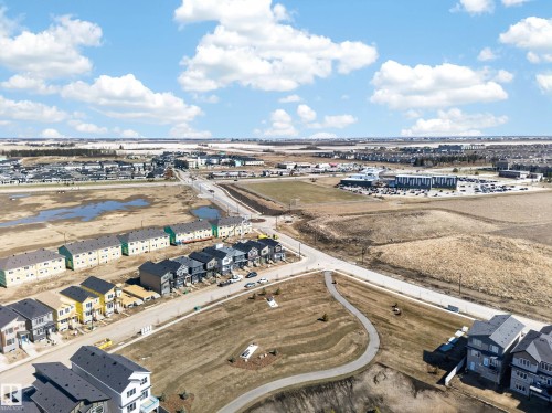 Aerial perspective showcasing a developing residential area with modern multi-story homes and townhomes, featuring a paved street system, sidewalks, and open green spaces - 408 Crystal Creek Link, Leduc, AB - Outdoor With View