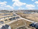 Aerial perspective showcasing a developing residential area with modern multi-story homes and townhomes, featuring a paved street system, sidewalks, and open green spaces - 408 Crystal Creek Link, Leduc, AB  - Outdoor With View 