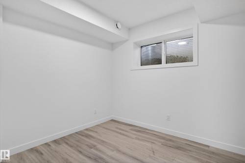 Bright room featuring a horizontal window with white trim, wood-finish flooring, white painted walls, and white baseboards - 408 Crystal Creek Link, Leduc, AB - Indoor Photo Showing Other Room