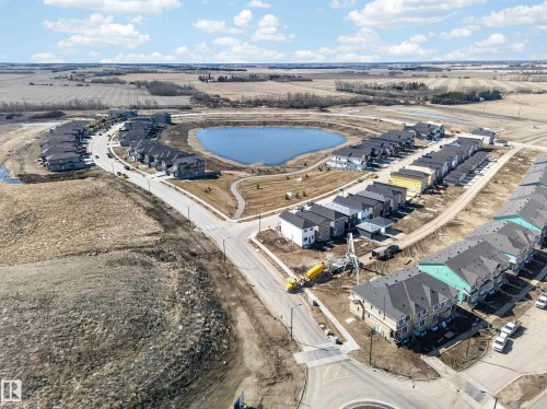 Aerial overview of a developing residential community featuring a central pond - 408 Crystal Creek Link, Leduc, AB - Outdoor With View