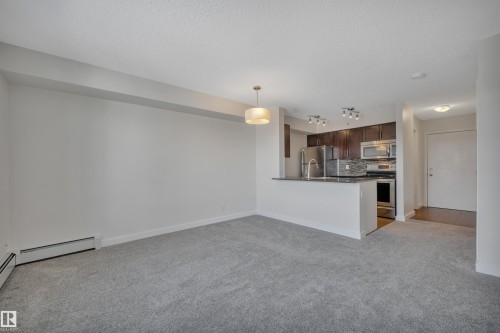 Living area featuring light grey carpeting, white walls, and a contemporary ceiling light fixture - 415 12035 22 Avenue, Edmonton, AB - Indoor Photo Showing Kitchen