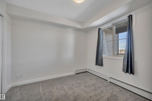 This room features light-colored walls, gray carpeting, and a window providing natural light - 415 12035 22 Avenue, Edmonton, AB - Indoor Photo Showing Other Room